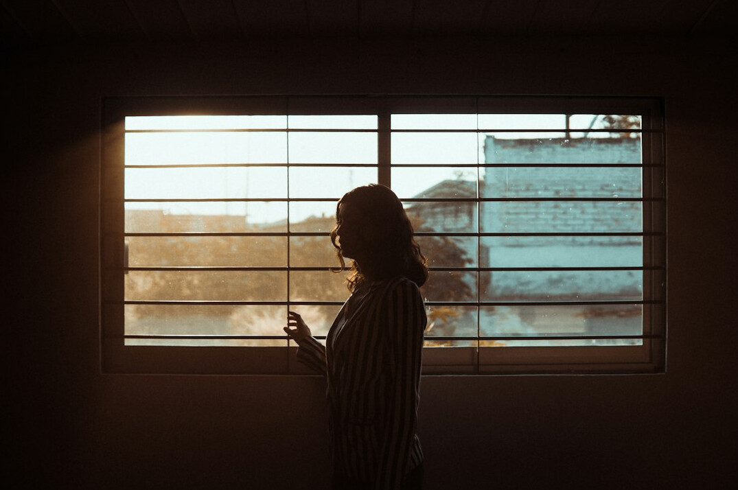 Brazilian woman sitting calmly by a window in quiet reflection